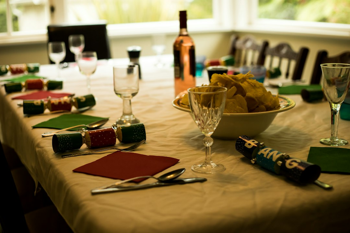 Long dinner table set for adult guests with a hosted poker-themed event table alongside